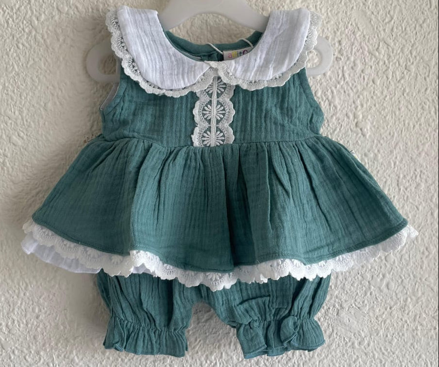 A toddler girl's two-piece outfit consisting of a sleeveless teal green dress with a white lace Peter Pan collar and matching ruffled trim, paired with matching teal green bloomers, hanging on a white hanger against a textured off-white wall.